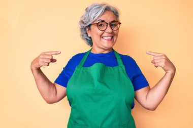 Önlük takan, gözlüklü, kendine güvenen, gülümseyen, kendini gururlu ve mutlu gösteren İspanyol bir kadın.. 