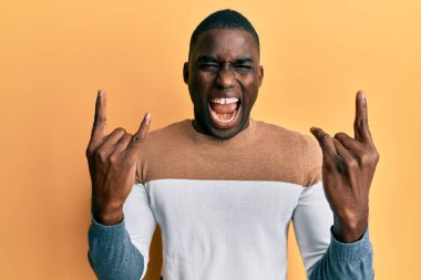 Sıradan kıyafetler giymiş, çılgın bir ifadeyle bağıran, elleri havada rock sembolü yapan genç bir Afrikalı Amerikalı. Müzik yıldızı. ağır kavram. 