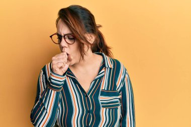 Günlük kıyafetler ve gözlük takan beyaz bir kadın kendini iyi hissetmiyor ve soğuk algınlığı veya bronşitin belirtisi olarak öksürüyor. sağlık hizmeti kavramı. 