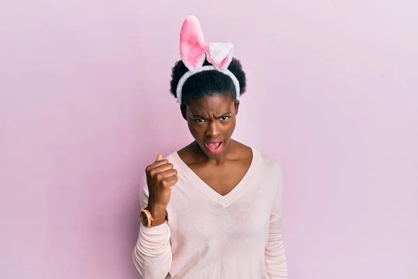 年轻的非洲裔美国女孩 戴着可爱的复活节兔子耳朵 怒气冲冲地举起拳头 怒气冲冲地大叫着 愤怒和好斗的概念 — 图库照片
