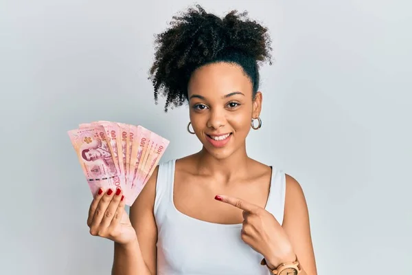 Chica Afroamericana Joven Sosteniendo Billetes Tailandeses Baht Sonriendo Feliz Señalando —  Fotos de Stock
