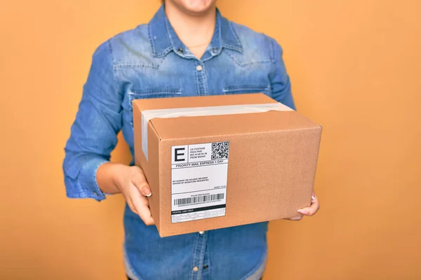 woman with cardboard box and package on color background