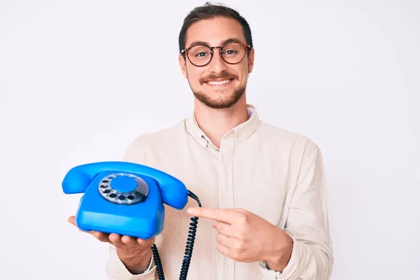 Joven Hombre Guapo Sosteniendo Teléfono Vintage Sonriendo Feliz Señalando Con —  Fotos de Stock