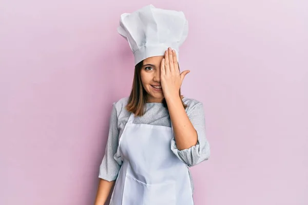 年轻美丽的女人穿着职业厨师的制服 头戴一顶帽子 一只眼睛蒙着 脸上带着自信的微笑 感情令人惊讶 — 图库照片