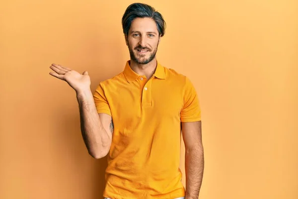 Joven Hombre Hispano Vistiendo Camiseta Amarilla Casual Sonriendo Alegre Presentando — Foto de Stock
