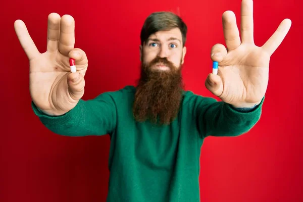 Redhead Man Long Beard Holding Two Different Pills Puffing Cheeks — Stock Photo, Image