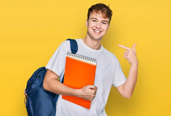 Młody Biały Mężczyzna Noszący Studencki Plecak Trzymający Książki Wskazujące Palcem — Zdjęcie stockowe