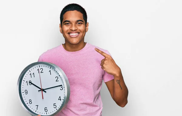 Joven Hombre Hispano Guapo Sosteniendo Gran Reloj Señalando Con Dedo —  Fotos de Stock