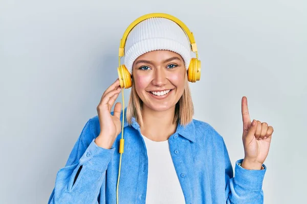 Красива Блондинка Слухає Музику Допомогою Навушників Посміхаючись Ідеєю Або Питанням — стокове фото