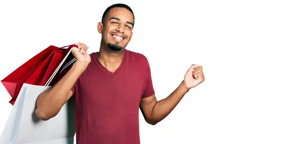 Joven Hombre Afroamericano Sosteniendo Bolsas Compras Gritando Orgulloso Celebrando Victoria — Foto de Stock