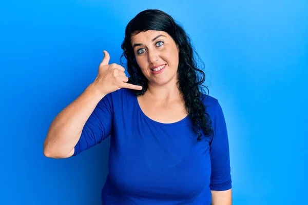 身材矮小的黑发女人穿着休闲的蓝色衬衫 微笑着用手和手指做着电话手势 就像在电话里说话一样 交流概念 — 图库照片