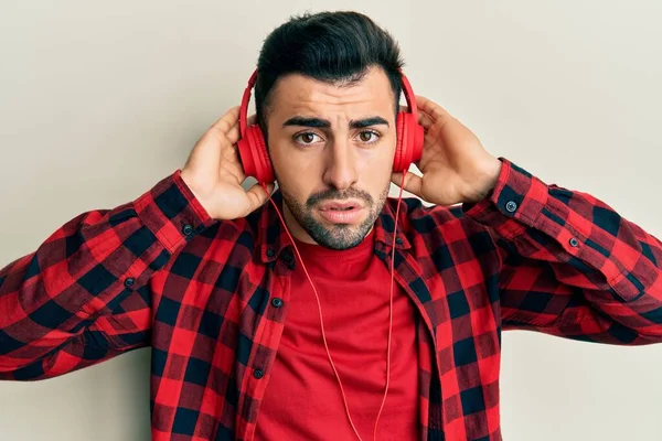 Young Hispanic Man Listening Music Using Headphones Clueless Confused Expression — Stock Photo, Image