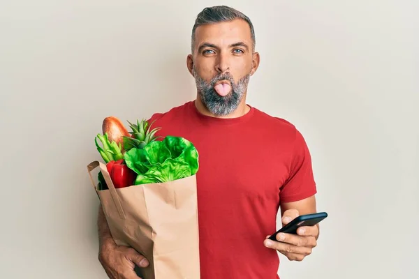 Hombre Guapo Mediana Edad Sosteniendo Bolsa Comestibles Usando Teléfono Inteligente —  Fotos de Stock
