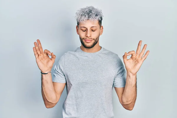 身穿休闲灰色T恤 头戴现代染发的年轻人放松了 闭上双眼微笑着 用手指做冥想动作 瑜伽概念 — 图库照片