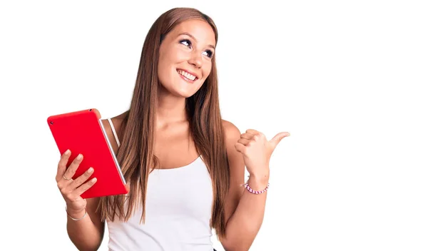 Joven Mujer Hispana Hermosa Sosteniendo Touchpad Apuntando Pulgar Hacia Lado — Foto de Stock