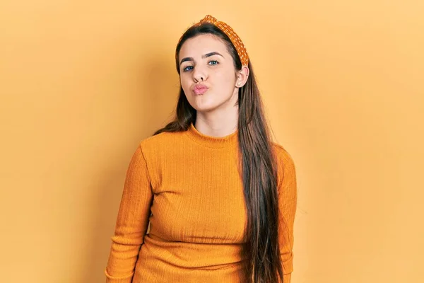 Joven Adolescente Morena Vistiendo Suéter Amarillo Casual Mirando Cámara Soplando — Foto de Stock