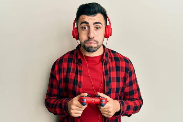 Joven Hispano Jugando Videojuego Sosteniendo Controlador Soplando Mejillas Con Cara —  Fotos de Stock