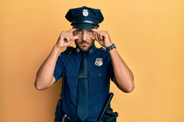 Snygg Latinamerikansk Man Klädd Polisuniform Försöker Öppna Ögonen Med Fingrar — Stockfoto