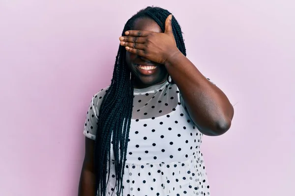カジュアルな服を着た若い黒人女性が笑顔で 驚きのために目を覆う顔で手で笑っています 視覚障害の概念 — ストック写真