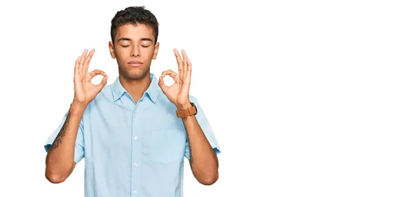 若いハンサムなアフリカ系アメリカ人の男性は カジュアルな服を着てリラックスし 目を閉じて指で瞑想ジェスチャーを行う笑顔 ヨガのコンセプト — ストック写真