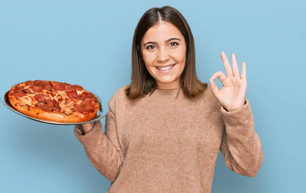 年轻美丽的女人拿着意大利披萨 手拿着手签 微笑着表示友善的手势 是个很好的象征 — 图库照片