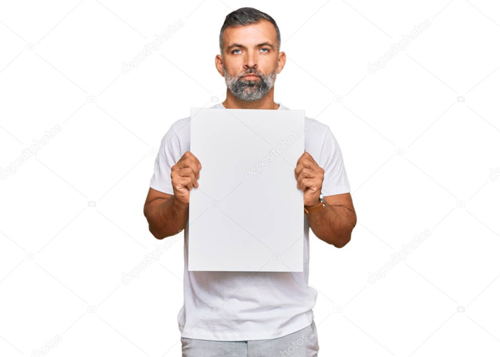 Middle age handsome man holding blank empty banner thinking attitude and sober expression looking self confident 