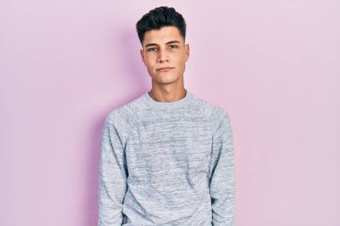 Günlük kıyafetler giyen genç İspanyol adam yüzünde ciddi bir ifadeyle rahatlamış. Basit ve doğal bir şekilde kameraya bakıyorsun.. 