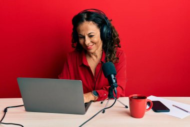 Güzel orta yaşlı bir kadın radyo stüdyosunda çalışıyor. Yüzünde mutlu ve havalı bir gülümseme var. şanslı kişi. 
