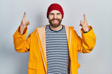 Sakallı, sarı yağmurluk giymiş, çılgın bir ifadeyle bağıran, elleri havada rock sembolü yapan beyaz bir adam. Müzik yıldızı. ağır müzik konsepti. 