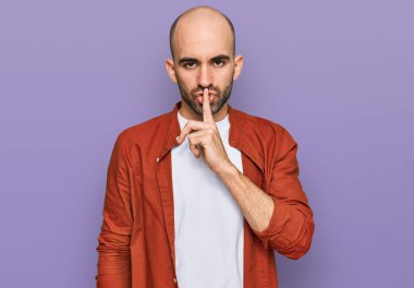 Gündelik kıyafetler giyen genç İspanyol adam parmakları dudaklarında sessiz olmak istiyor. sessizlik ve gizli konsept. 