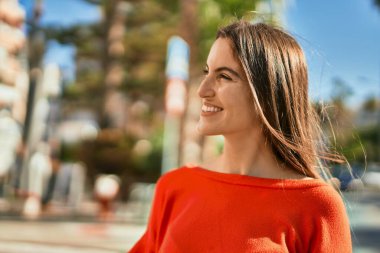 Genç İspanyol kadın gülümseyerek şehirde mutlu mesut dikiliyor..