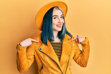 Sarı şapkalı, deri ceketli, kendine güvenen, yüzünde gülümseme olan, kendini gururlu ve mutlu gösteren genç modern bir kız.. 