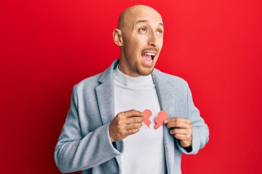 Kırık kalp kâğıdı tutan kel bir adam kızgın ve kızgın bağırıyor öfkeyle bağırıyor. öfke ve agresif konsept. 