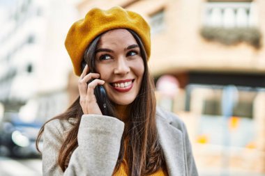 Genç İspanyol kız gülümsüyor. Şehirdeki akıllı telefondan konuşuyor..