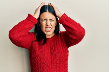 Kışlık yün kazak giyen güzel esmer kadın acı ve migren yüzünden çaresiz ve stresli baş ağrısından muzdarip. Eller başının üstünde.. 