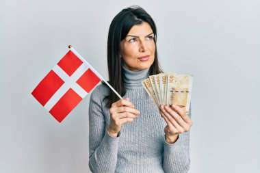 Danimarka bayrağı ve Krone banknotları taşıyan genç İspanyol kadın gülümsüyor ve başka tarafa bakıyor.. 
