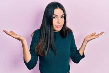 Genç esmer kadın, sıradan bir kazak giyiyor, habersiz ve kolları açık, hiçbir fikrim yok ve şüpheli bir yüzüm var.. 