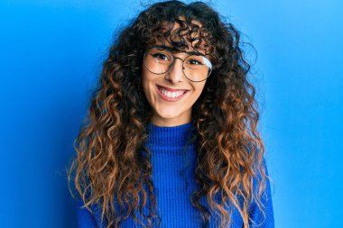 Yüzünde mutlu ve havalı bir gülümseme olan günlük kıyafetler ve gözlük takan İspanyol genç bir kız. şanslı kişi. 