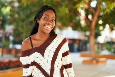 Genç Afrikalı Amerikalı kadın parkta mutlu bir şekilde gülümsüyor..