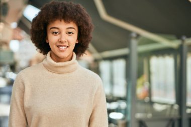 Genç İspanyol kız gülümseyerek şehirde mutlu mesut dikiliyor..