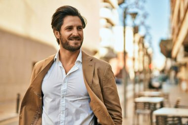 Genç İspanyol işadamı gülümseyerek şehirde mutlu mesut duruyor..