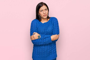 Latin kökenli genç bir kadın günlük kıyafetler giyiyor. Kış soğuğu için titriyor ve donuyor. Yüzünde üzgün ve şok ifadesi var. 