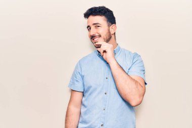 Gündelik giysiler giyen genç İspanyol adam kameraya kollarını kavuşturup çenesine dokunarak gülümsüyor. Olumlu düşünmek. 