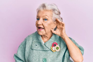 Kıdemli, gri saçlı, günlük kıyafetler giyen, el pençe divan gülümseyen, dedikoduları ve dedikoduları dinleyen bir kadın. Sağırlık kavramı. 