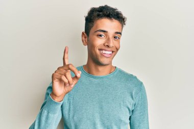 Genç, yakışıklı, Afro-Amerikalı, gündelik kıyafetler giymiş, bir fikir veya soruyla gülümseyen, mutlu bir yüzle işaret eden, bir numara. 