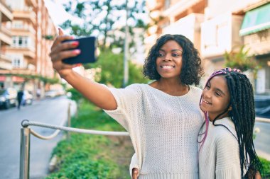 Afrikalı Amerikalı anne ve kızı parkta sarılıp selfie çekiyorlar..