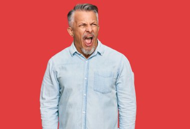 Orta yaşlı, gri saçlı, günlük kıyafetler giyen kızgın ve kızgın çığlık atan sinirli, öfkeyle bağıran bir adam. öfke ve agresif konsept. 