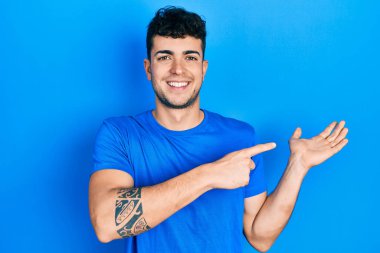 Günlük mavi tişört giyen genç İspanyol adam kameraya hayret ediyor ve gülümsüyor.. 