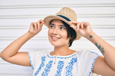 Tatildeki genç Latin turist kız gülümseyerek şehirde mutlu bir şekilde yürüyor..