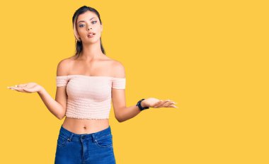 Gündelik kıyafetler giyen genç ve güzel bir kadın. Hiçbir fikri olmayan, kolları açık ve kafası karışık bir kadın.. 